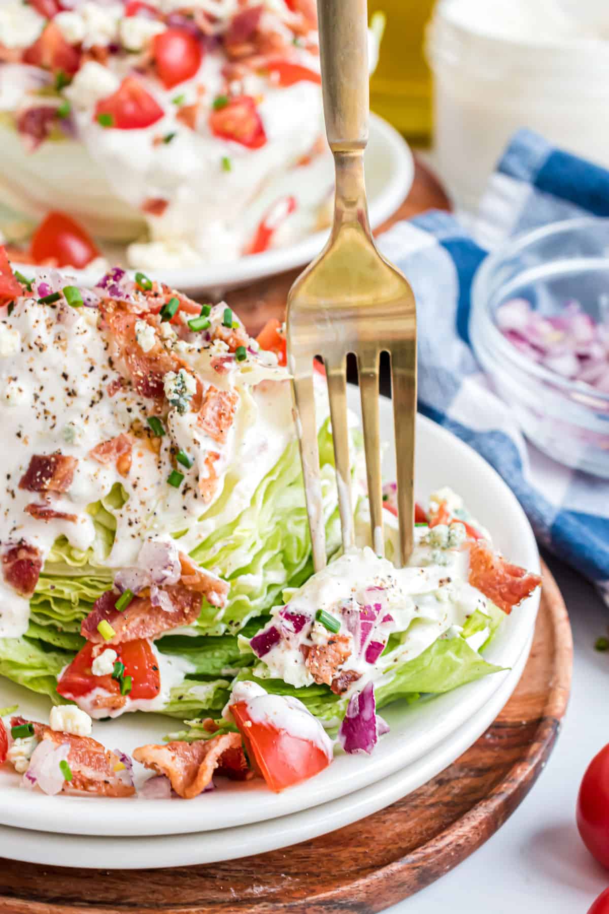 Wedge salad on a white plate with a bite being taken.