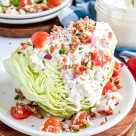 Hunk of wedge salad with dressing on a white plate.