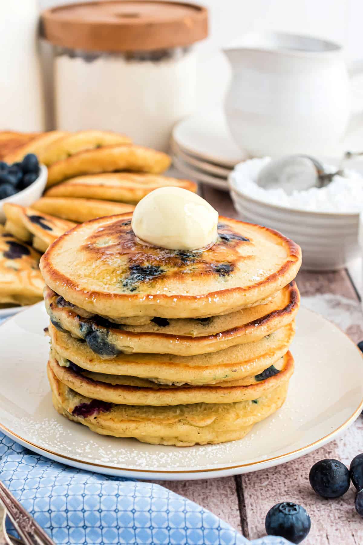 Stack of blueberry pancakes with butter on top.