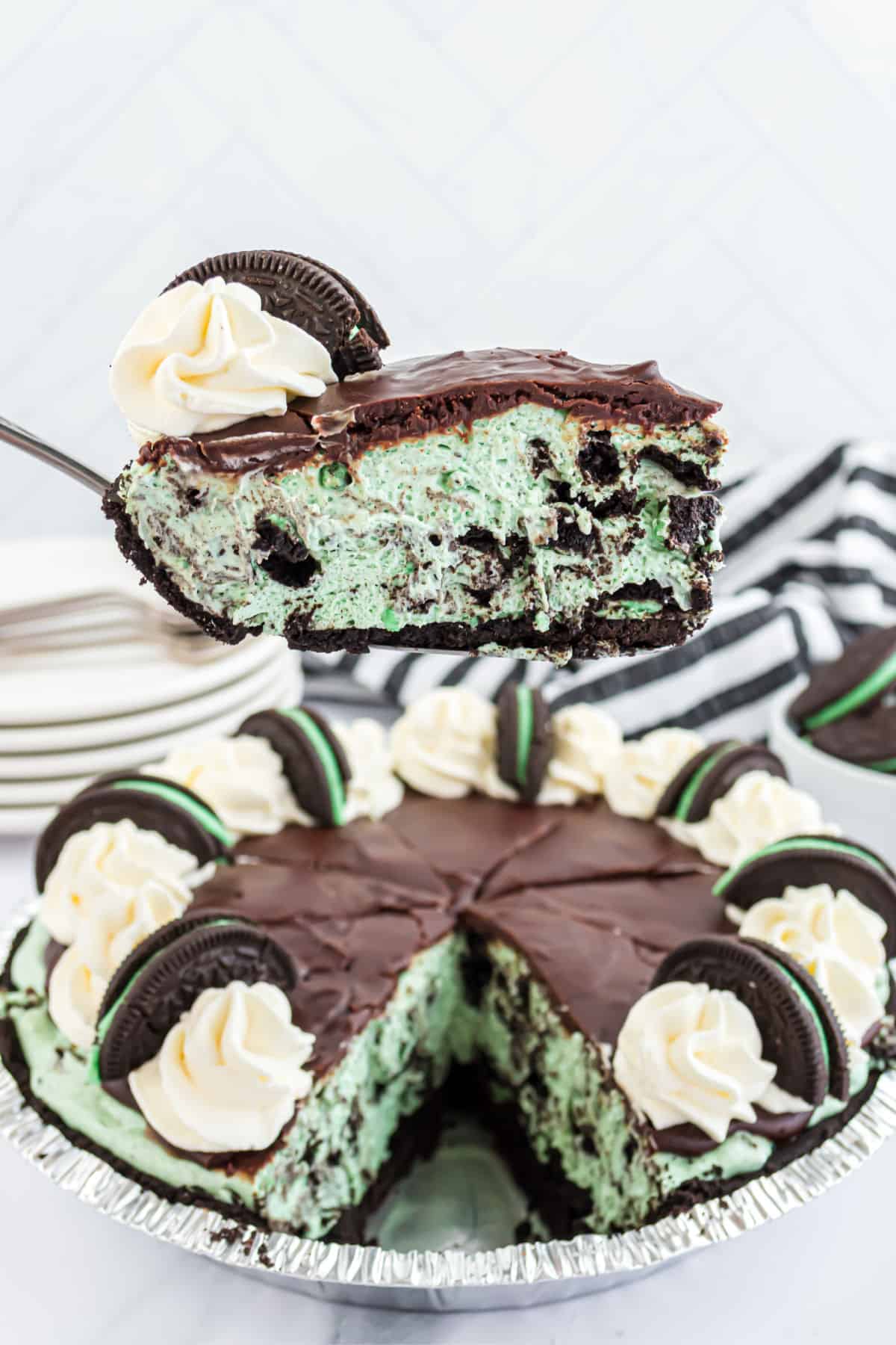 Slice or mint oreo cheesecake being lifted out of pan.