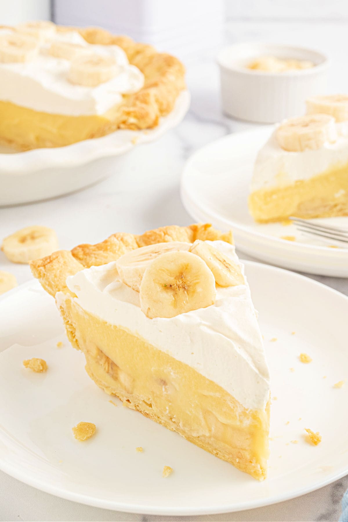 Slice of banana cream pie served on a white plate.