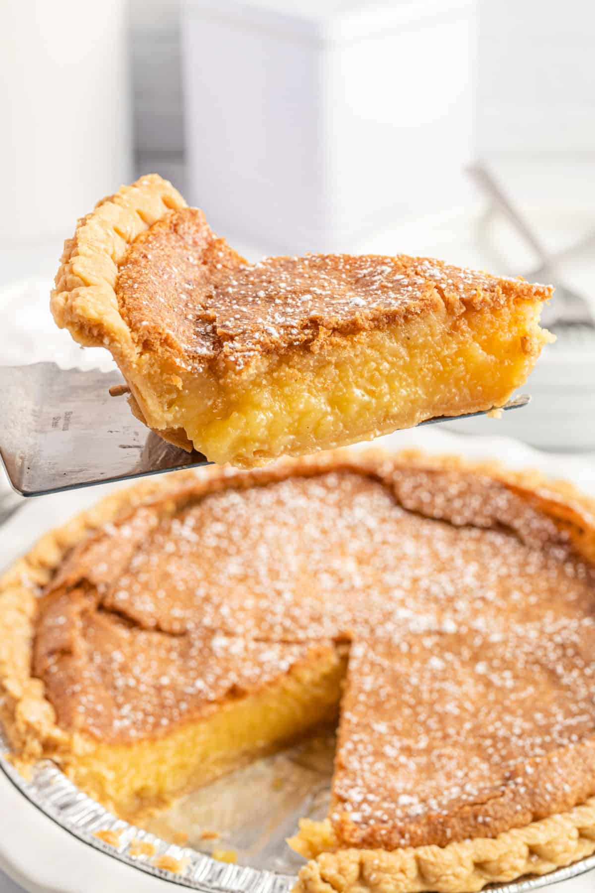 Slice of chess pie being lifted out of pie plate.