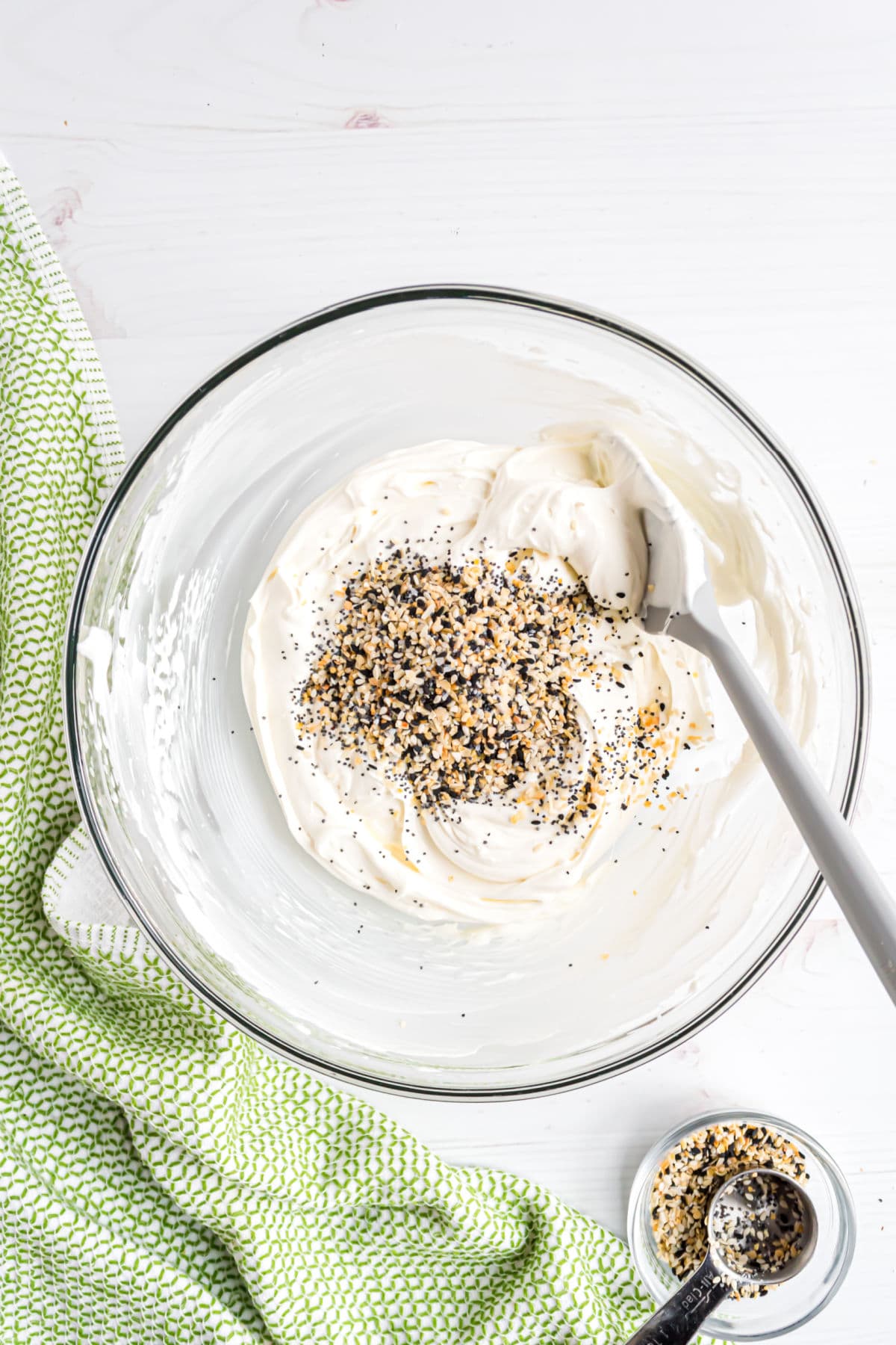 Clear mixing bowl with everything bagel dip to mix.