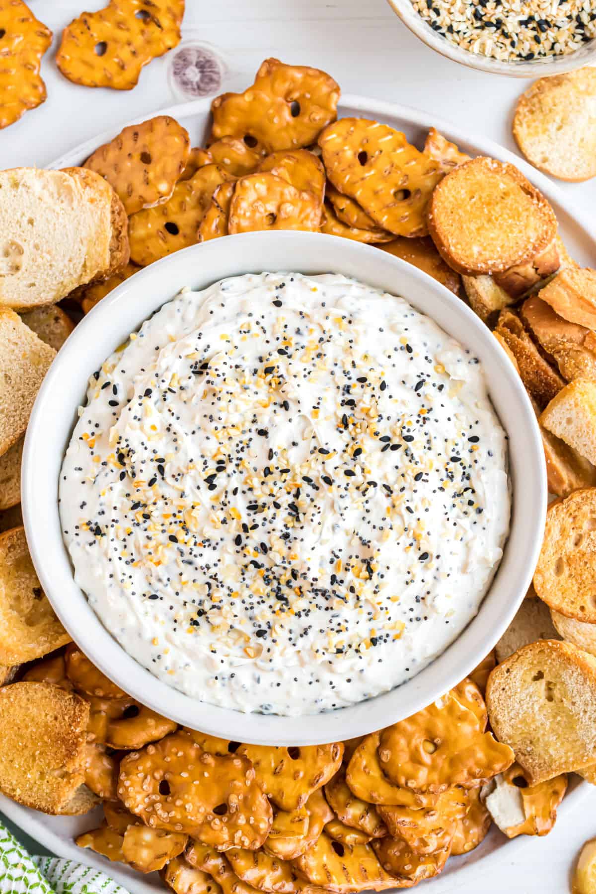 Everything bagel dip in a bowl with pretzels and bagel chips.