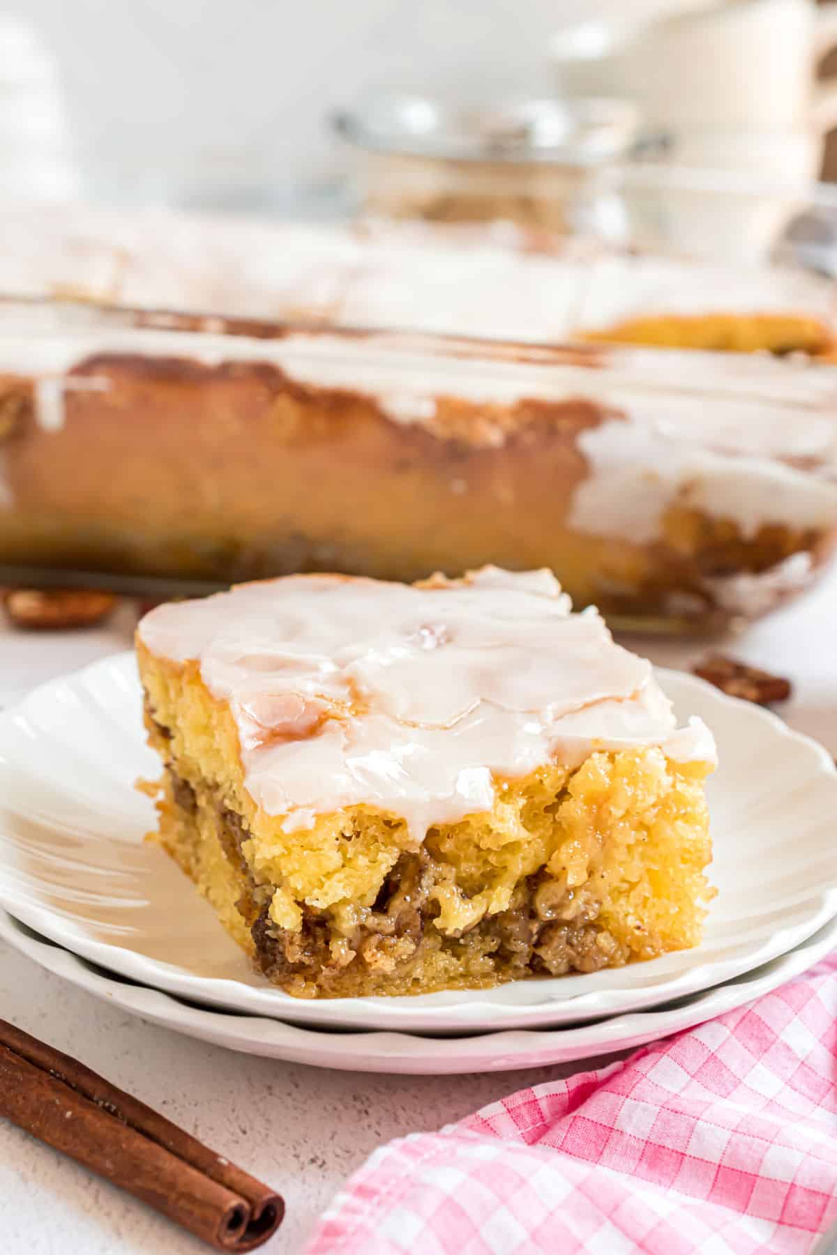 Slice of honey bun cake on a stack of white plates.