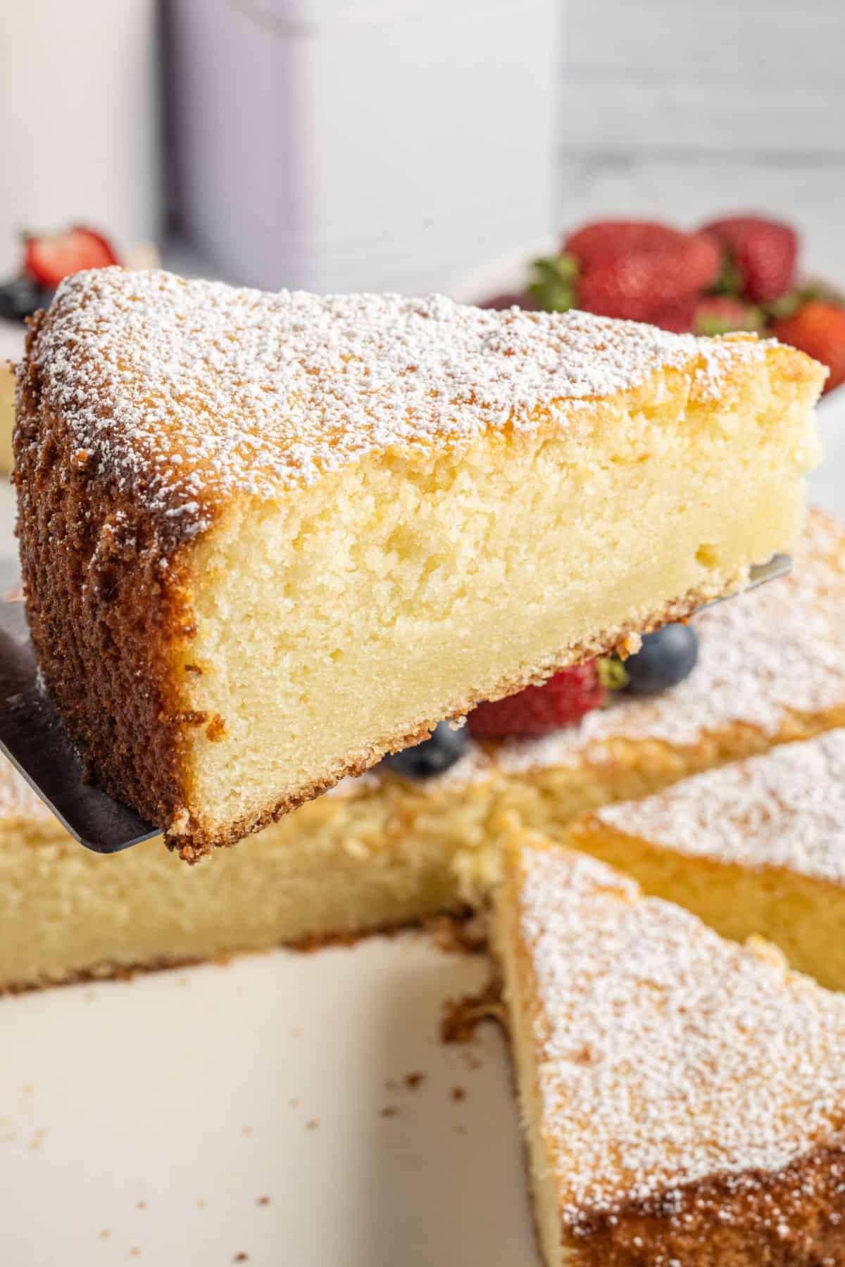 Slice of lemon ricotta cake being lifted out of pan.