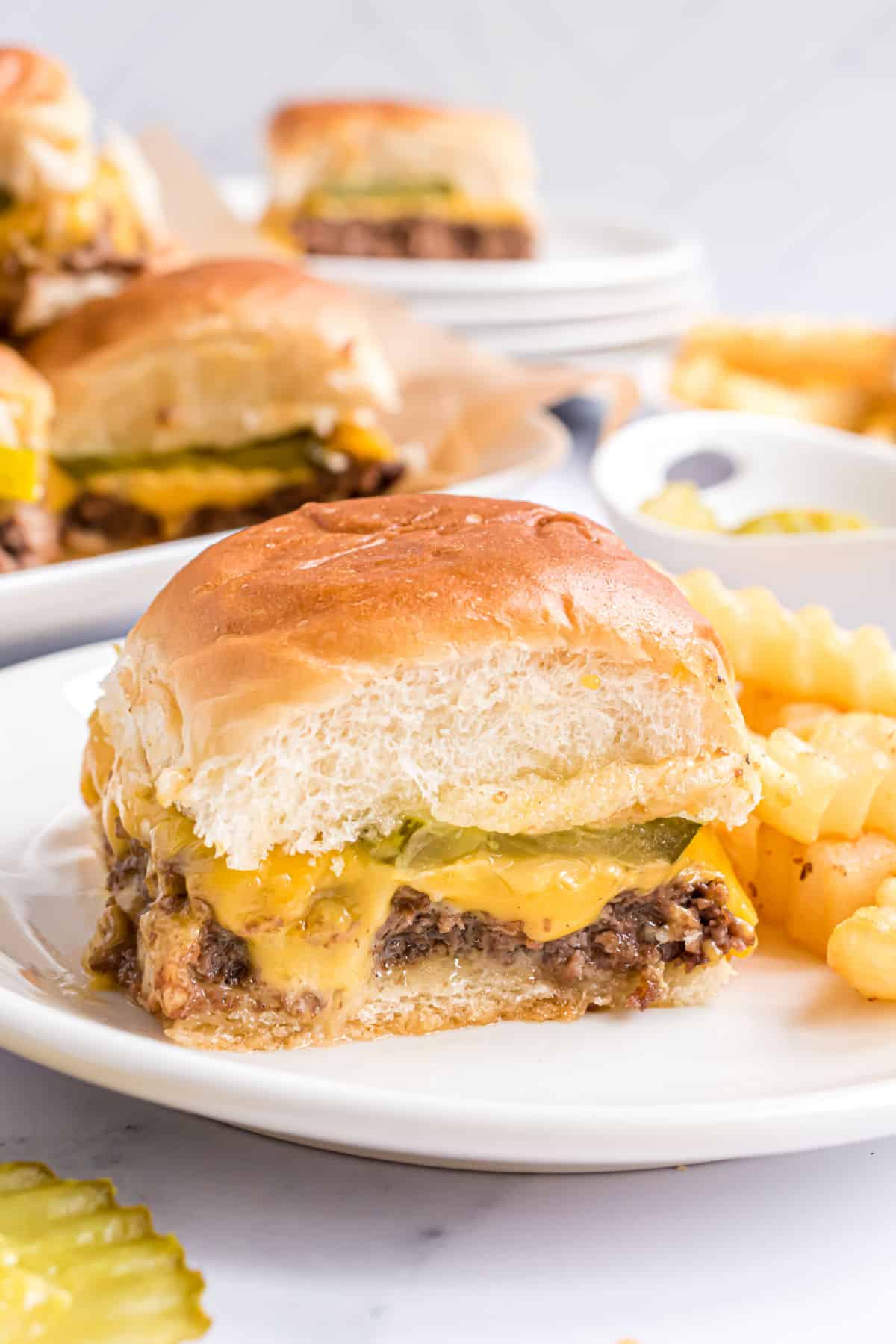 White castle slider served on a white plate with french fries.