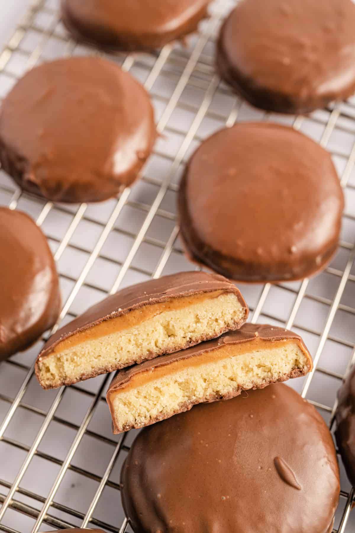 Tagalong cookies on a wire rack with one broken in half.