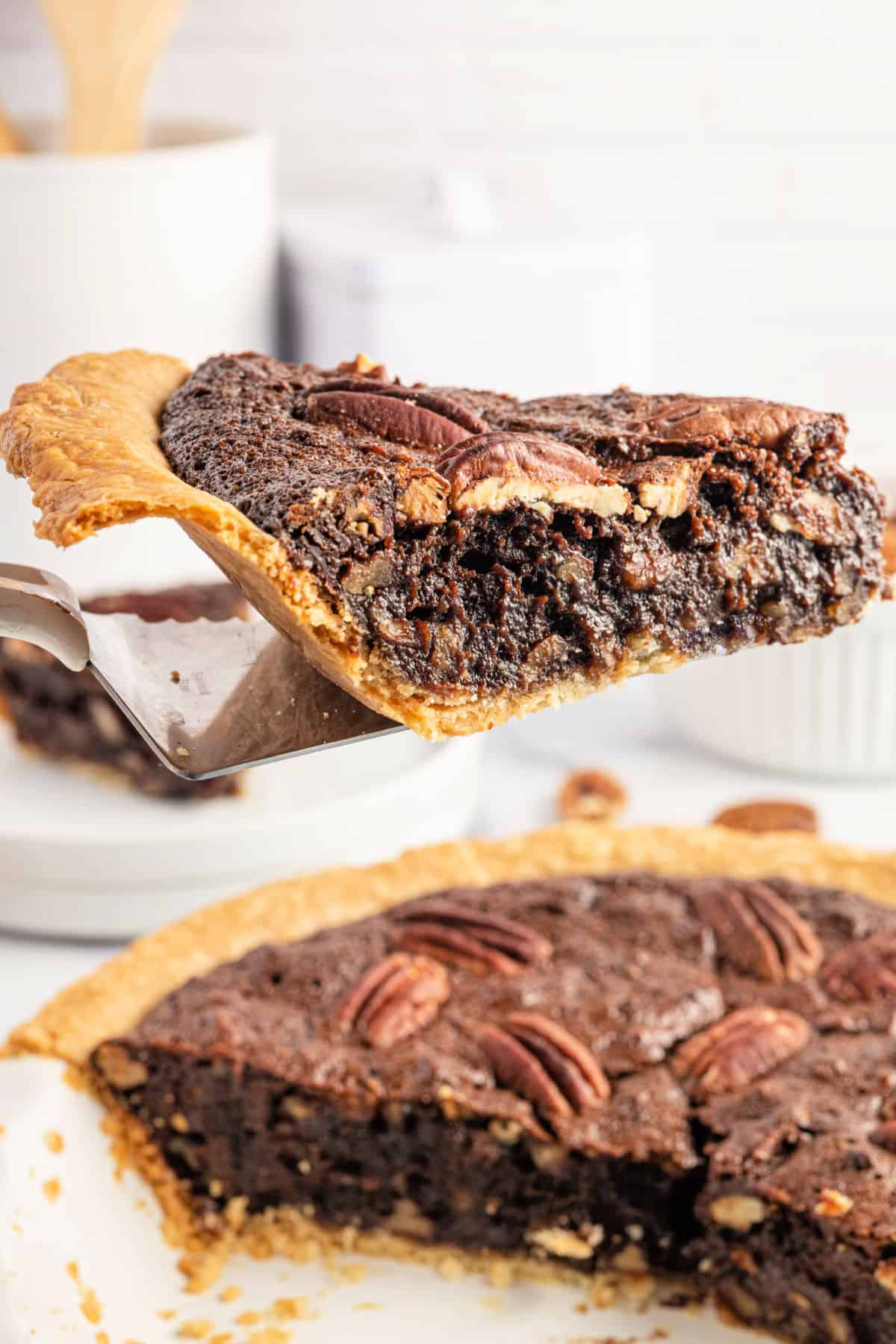 Slice of chocolate pecan pie being served from the pan.