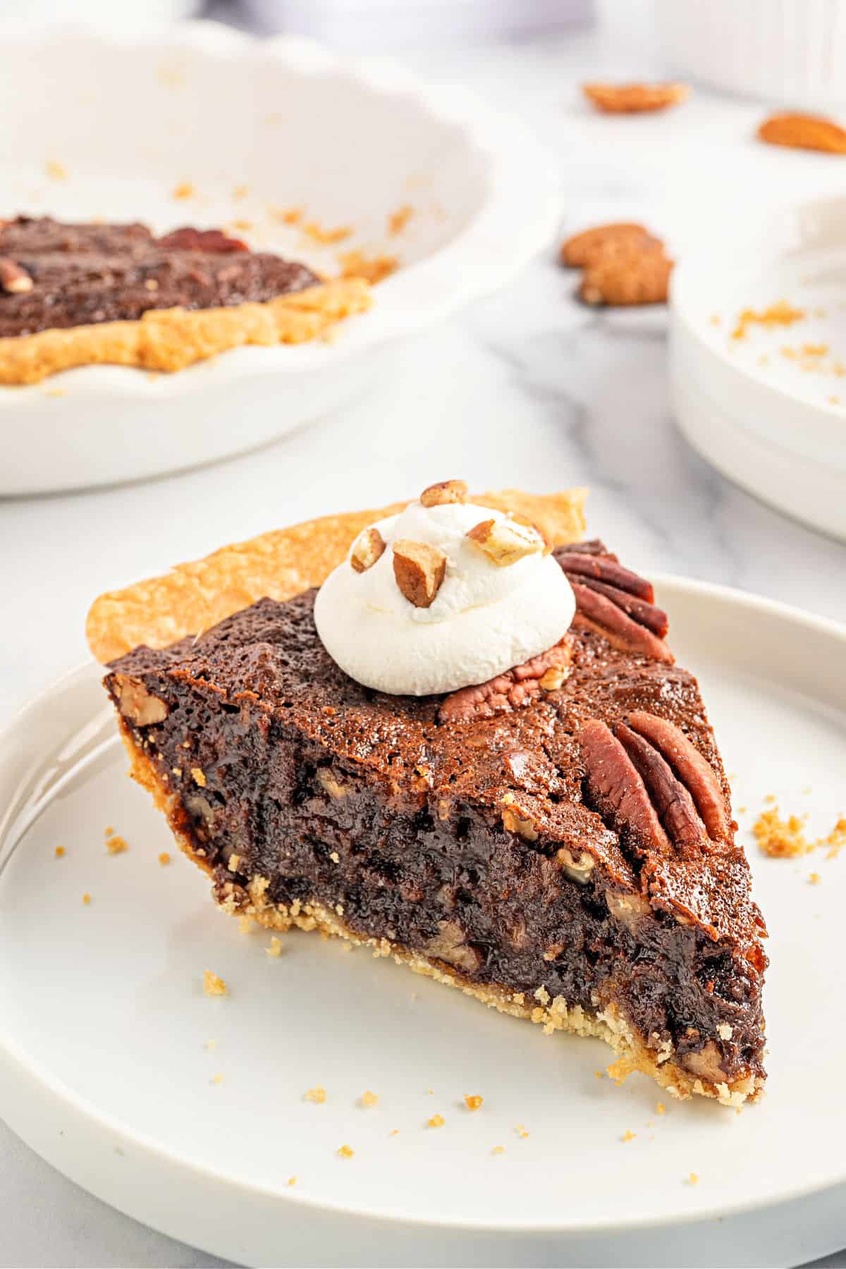 Slice of chocolate pecan pie with a dollop of whipped cream.