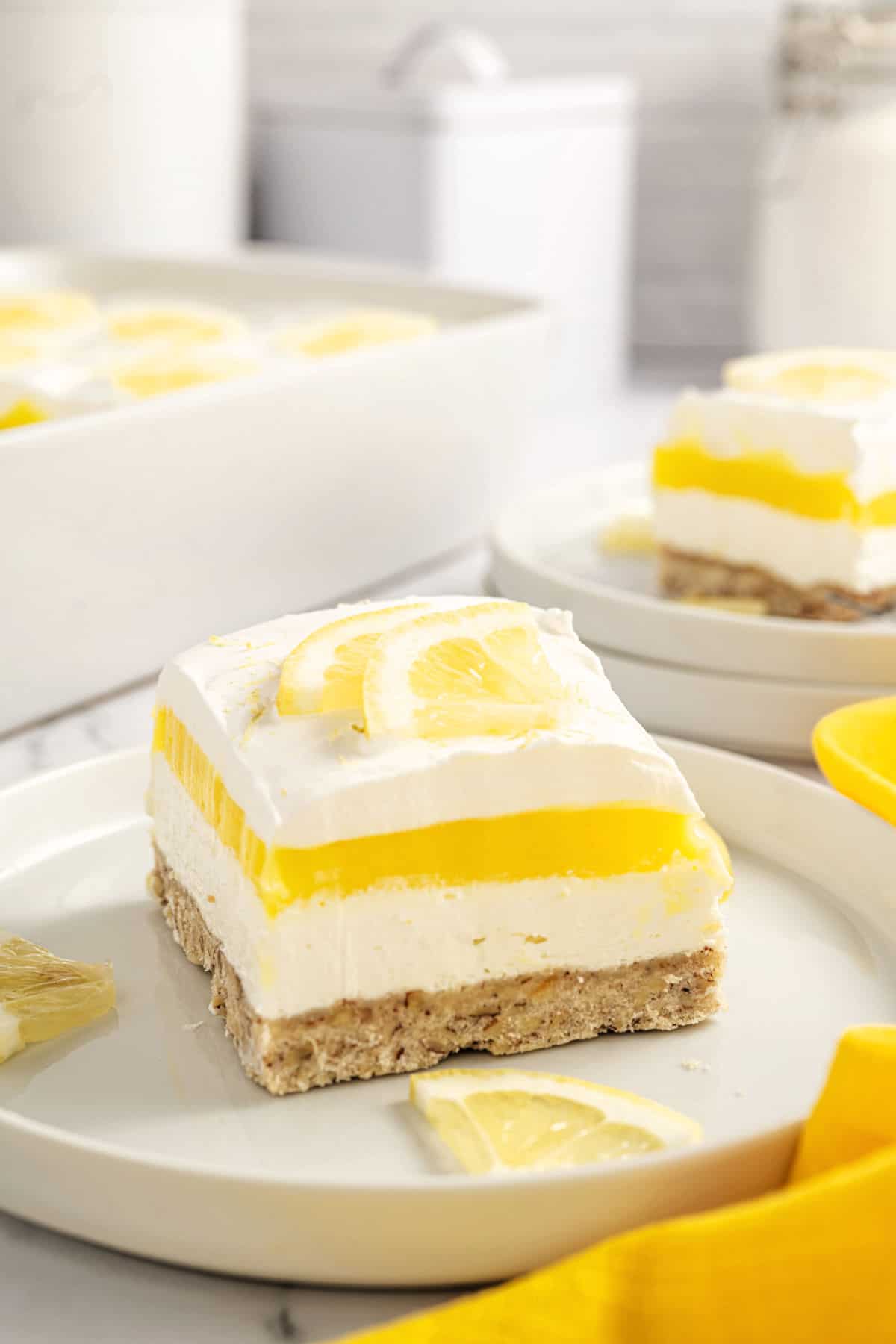 Slice of lemon lasagna layered dessert on a white plate.