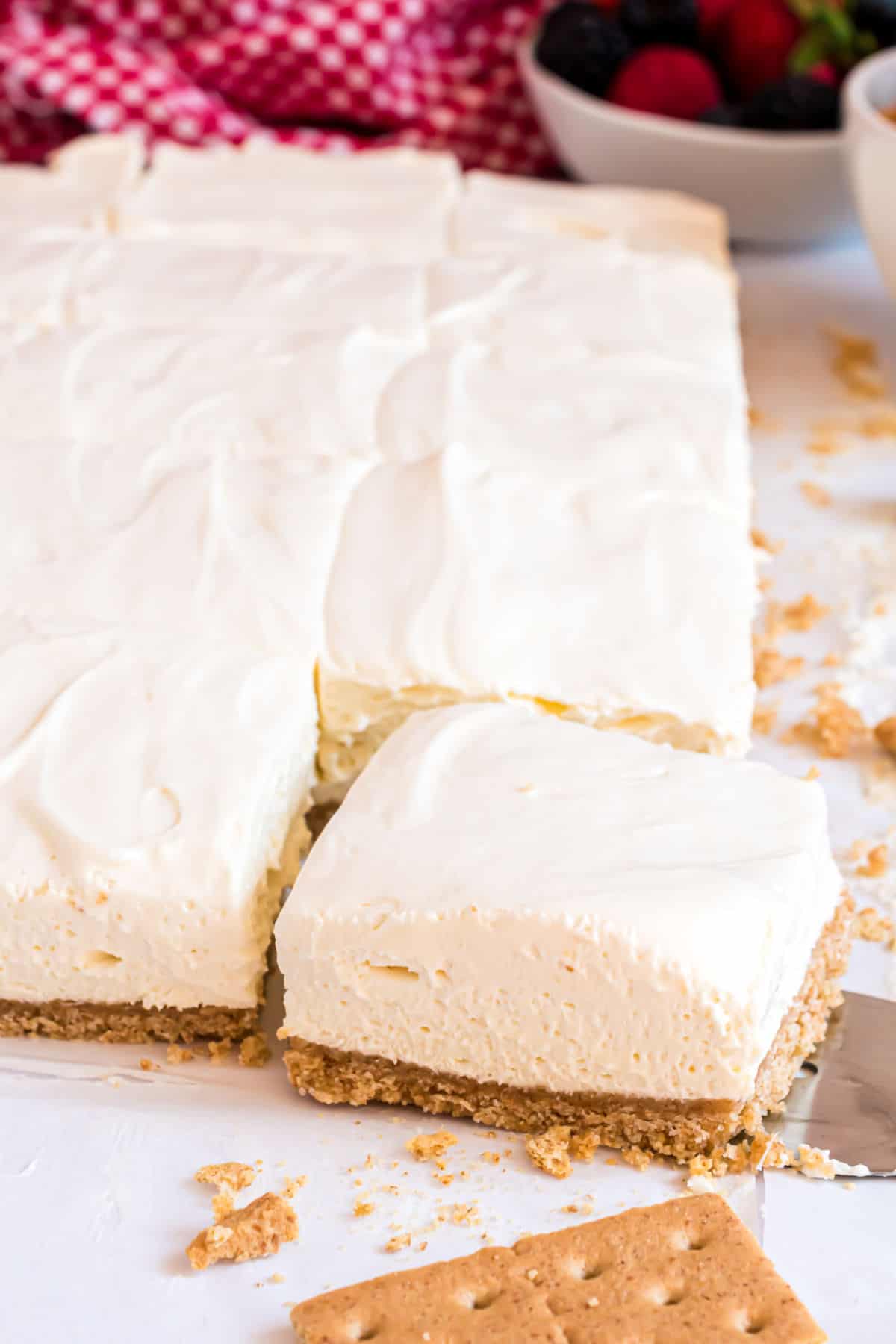 Cheesecake bars with one slice being removed with a spatula.