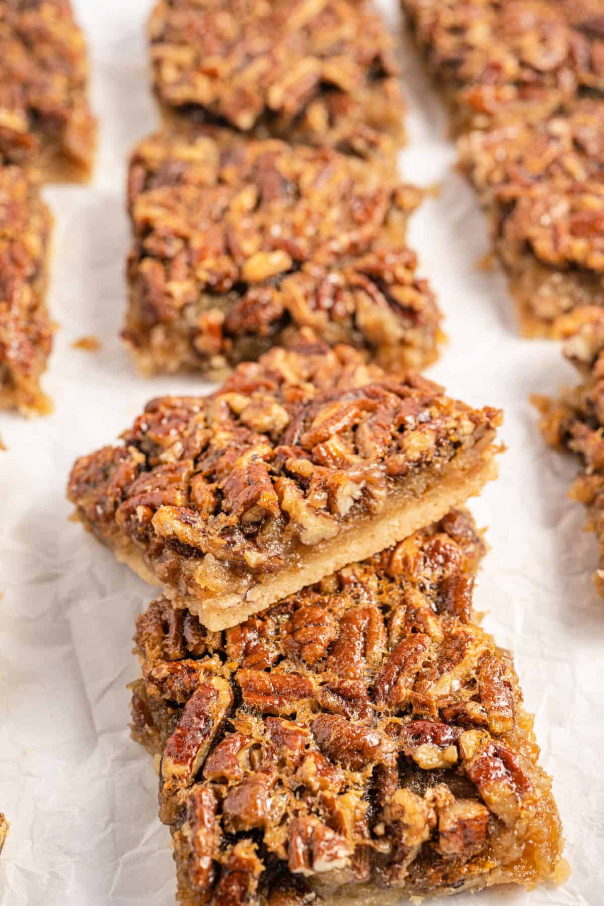 Pecan pie bars stacked on parchment paper.