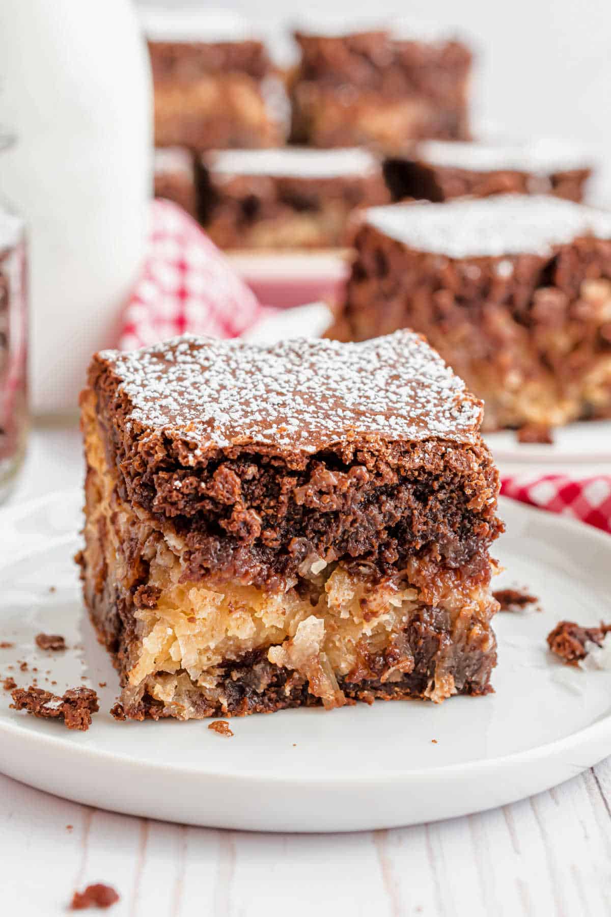 Thick piece of brownie with a coconut filling on a white plate.