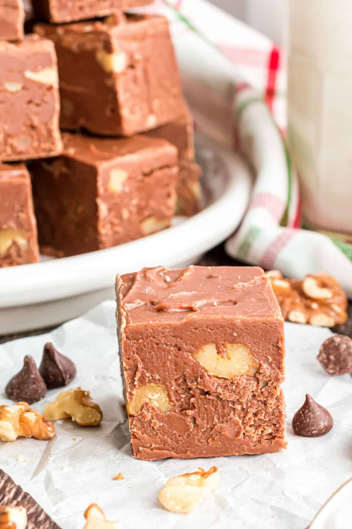 Piece of chocolate fudge with walnuts on parchment paper.