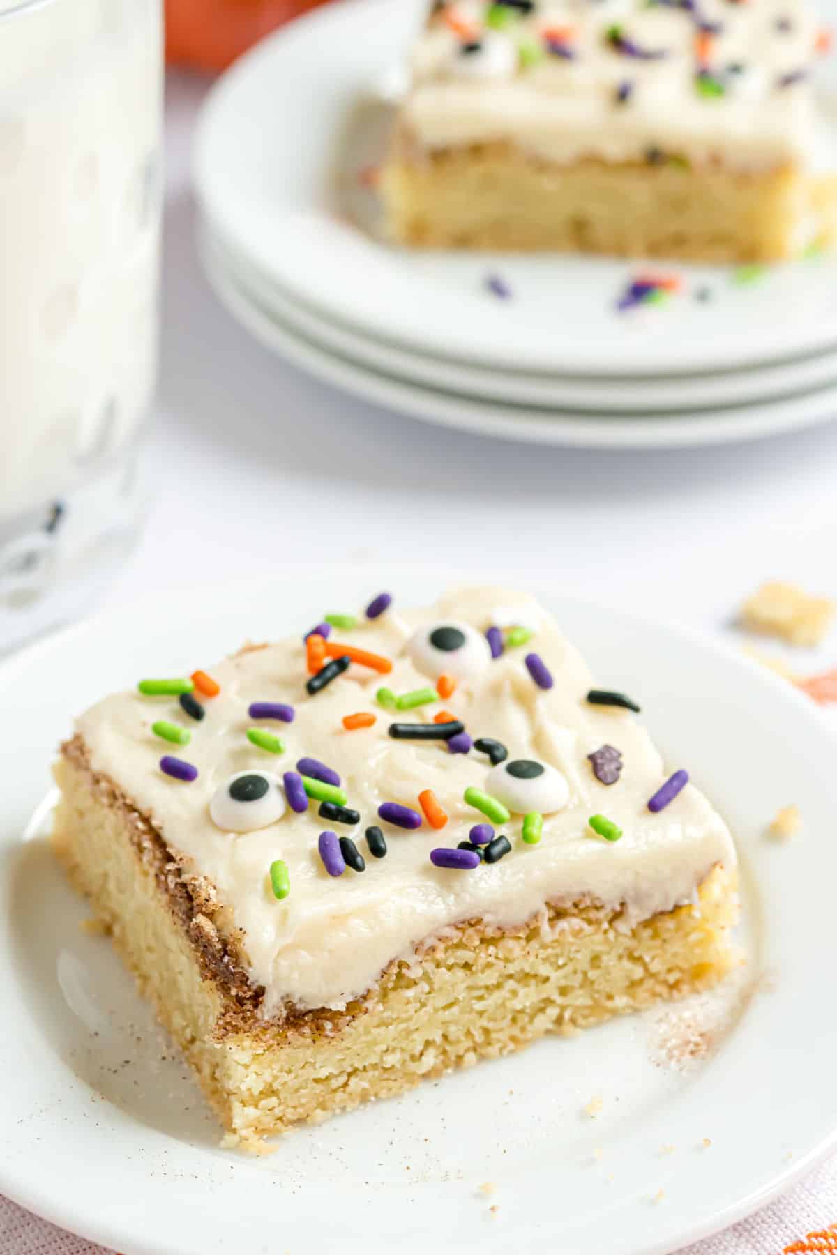 Snickerdoodle cookie bars with vanilla frosting and sprinkles on a white plate.