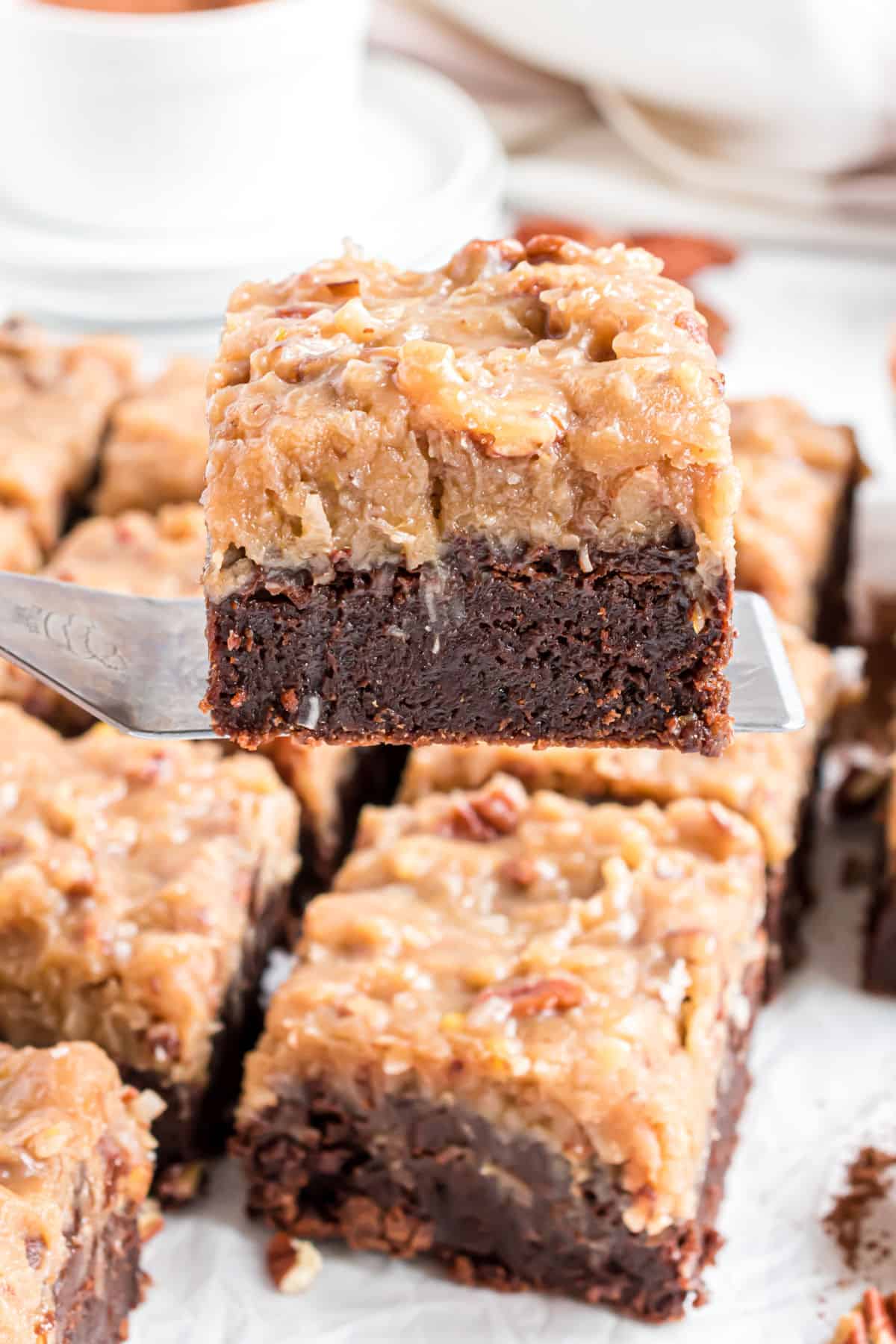 Slice of german chocolate brownies being lifted out of pan.