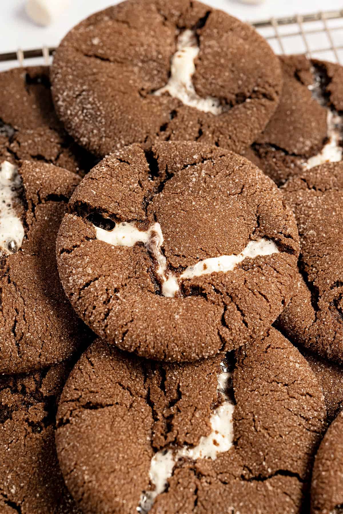 Chocolate marshmallow cookies stacked on a wire rack.