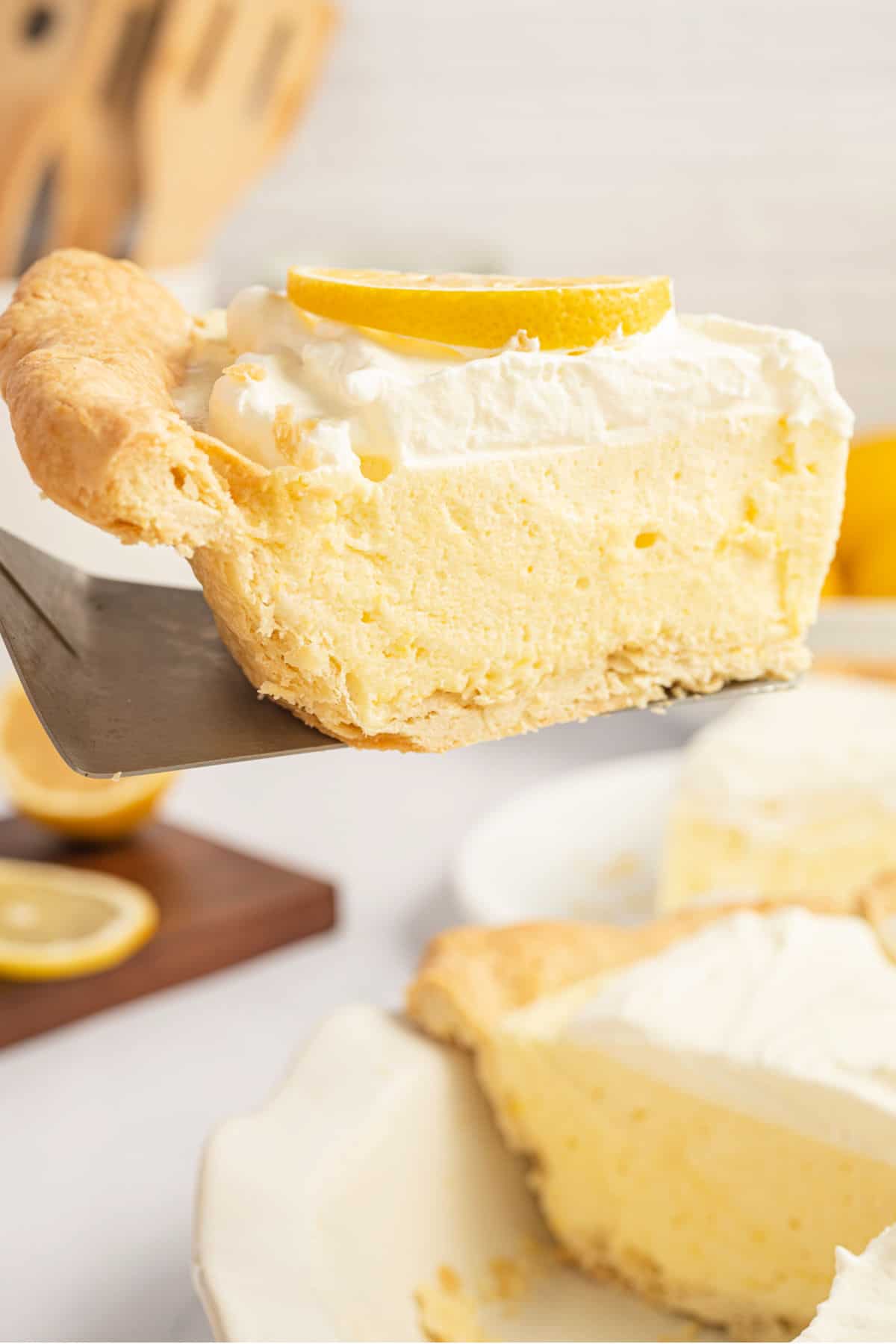 A slice of lemon chiffon pie being lifted out of pie plate.
