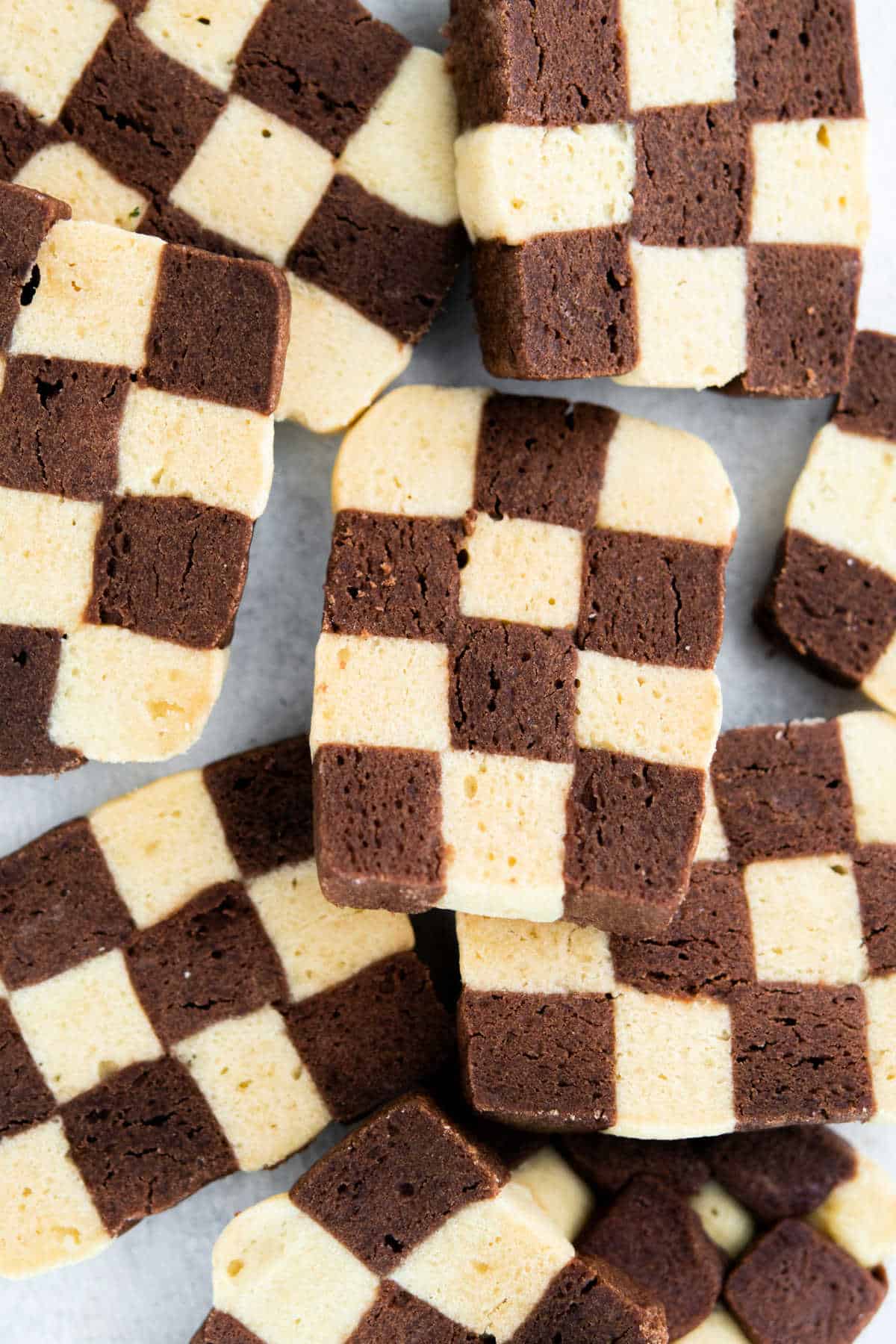 Black and white checkerboard cookies stacked on parchment paper.