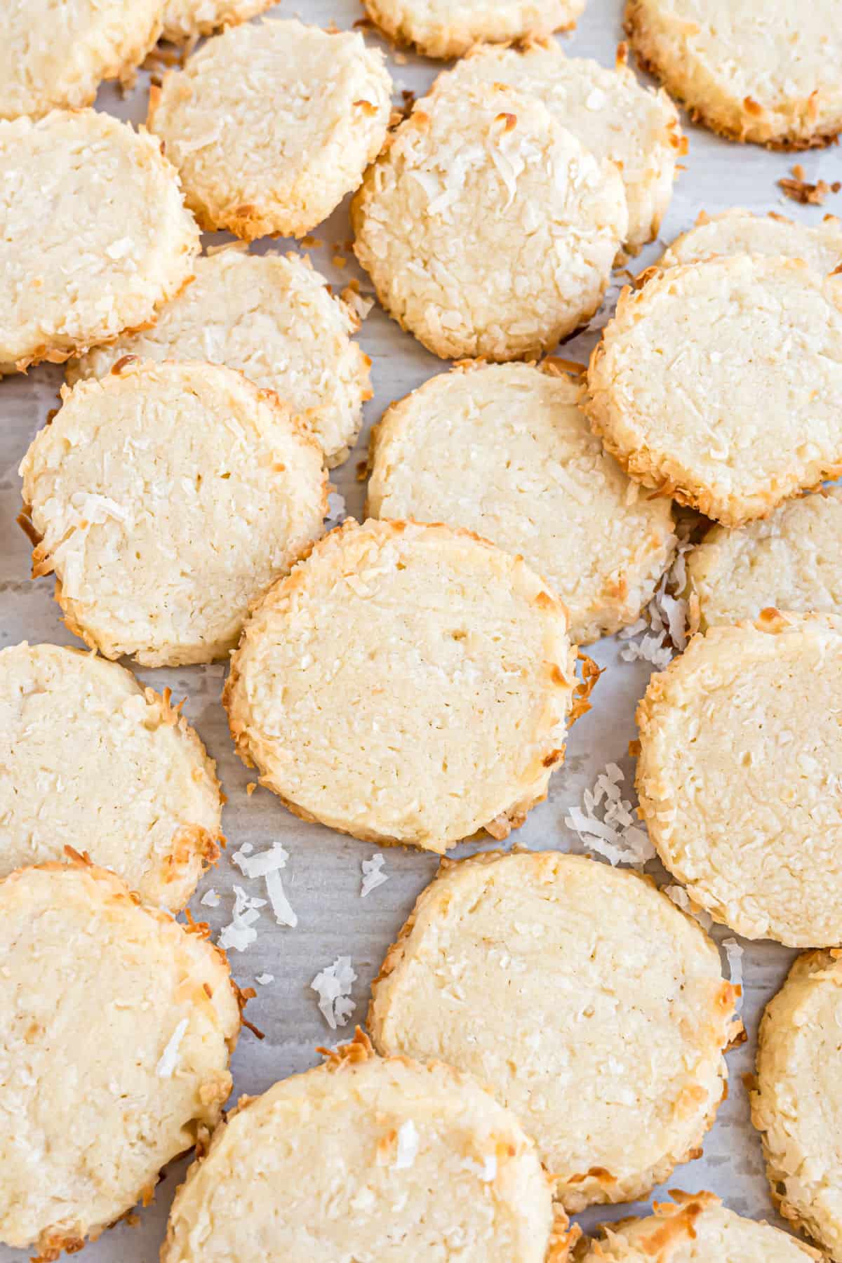 Coconut slice-and-bake cookies stacked on a baking sheet.