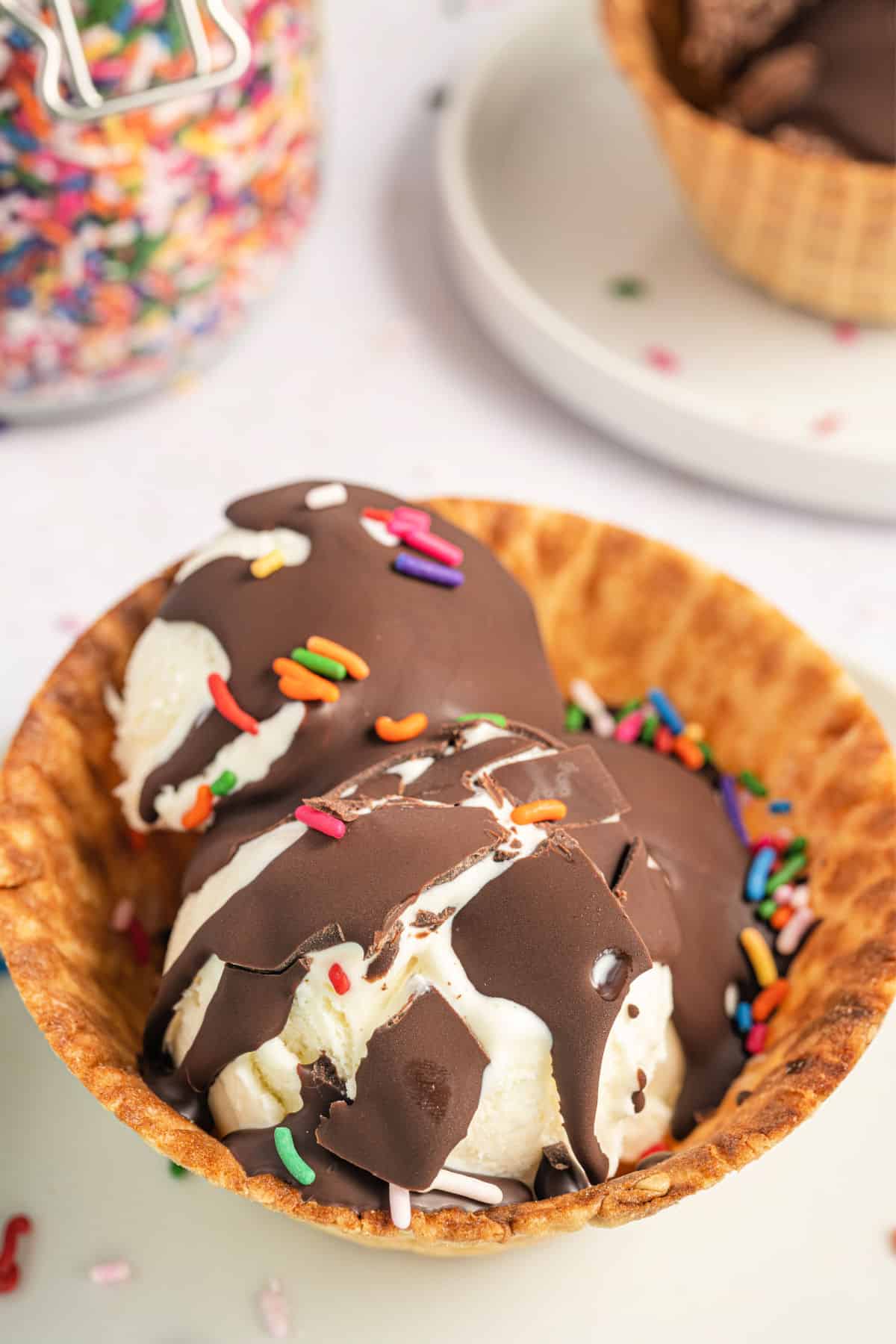 Chocolate topping with cracks over a vanilla ice cream waffle bowl.