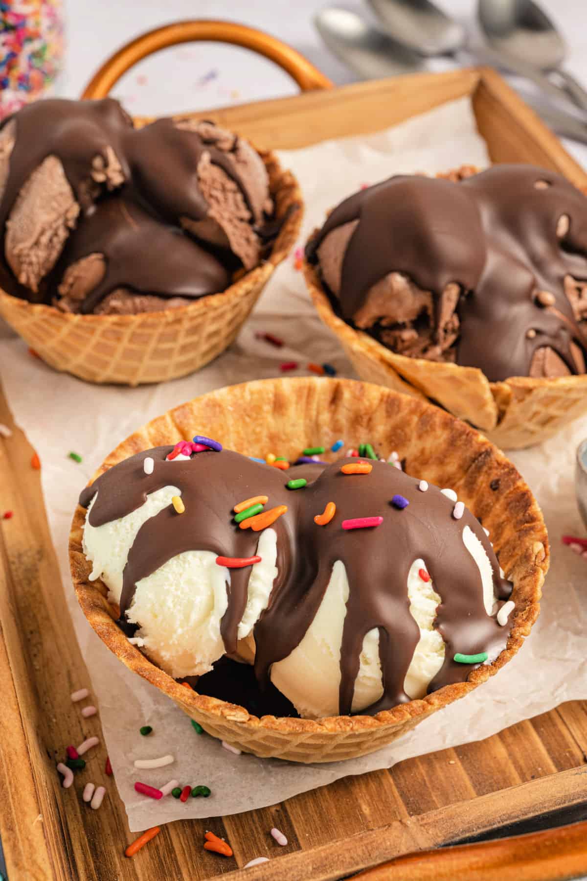 Magic shell chocolate drizzled over three waffle bowls of ice cream.
