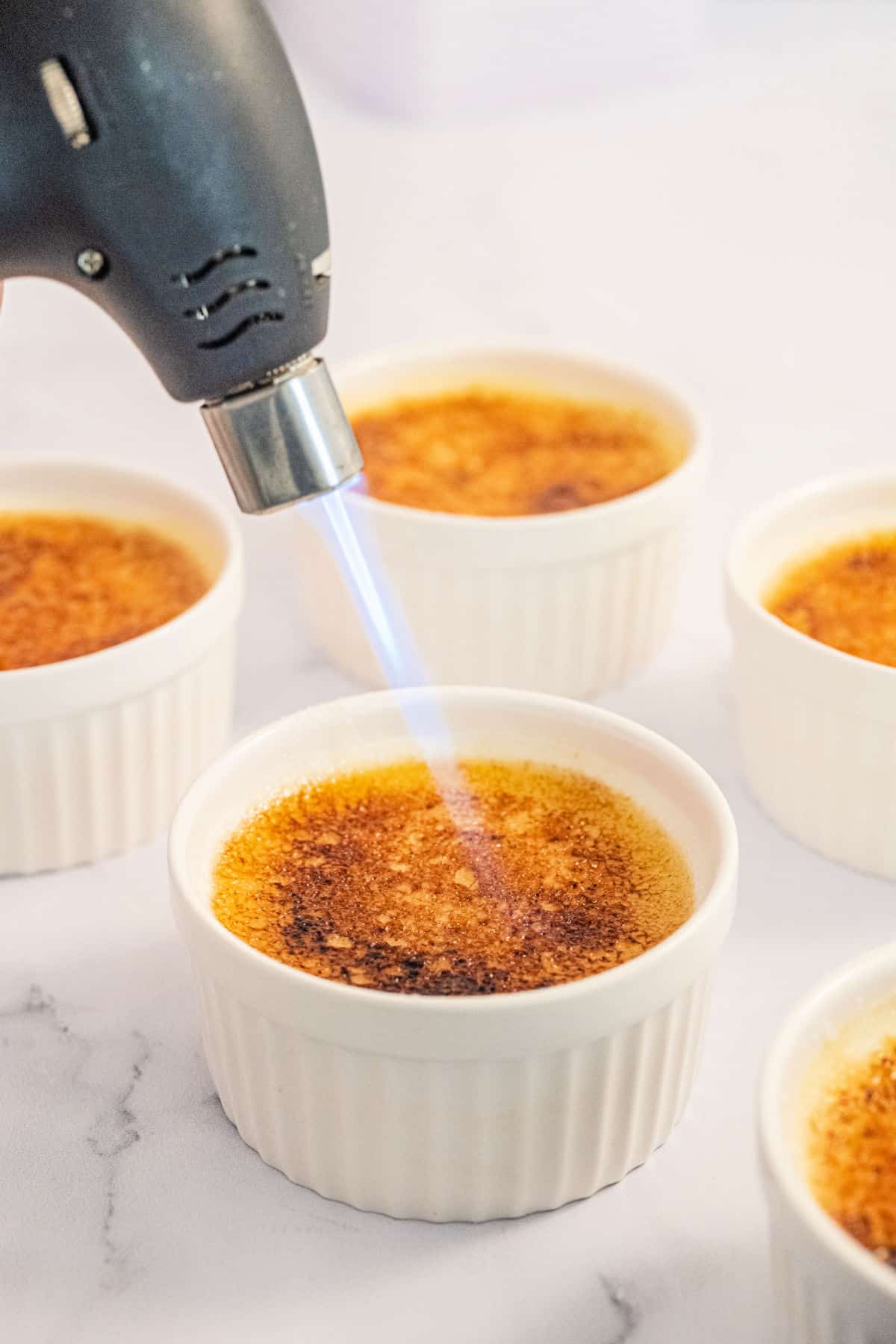 Torch heating sugar on creme brulee.