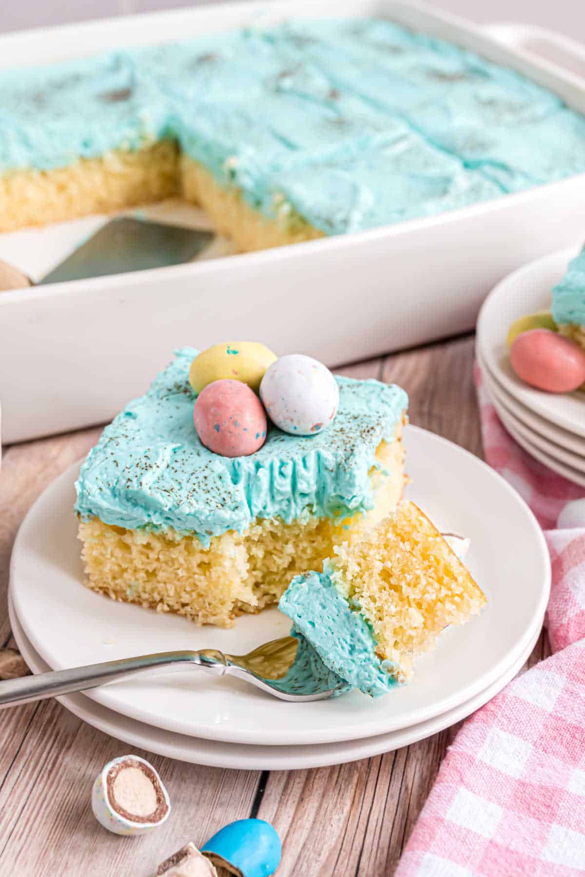 Slice of yellow cake with blue frosting and bite taken out.