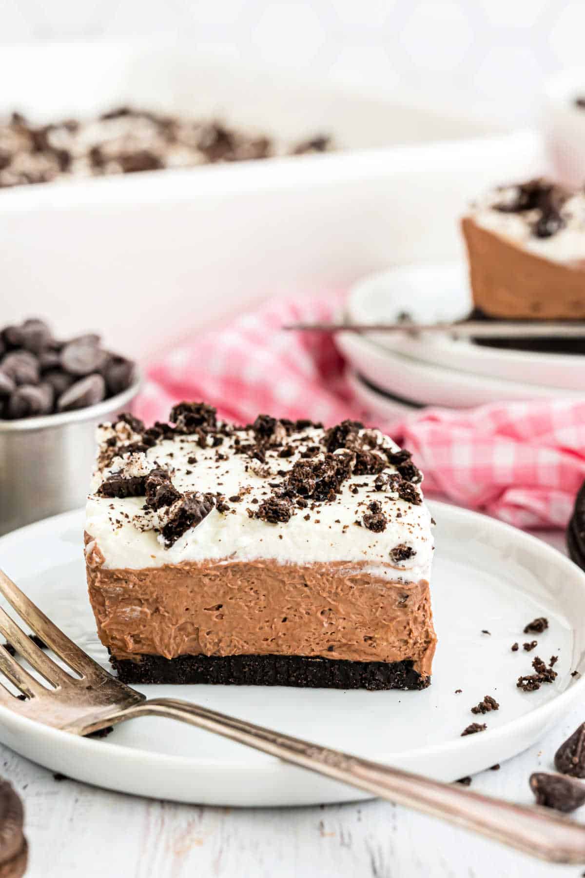 Slice of chocolate cheesecake with whipped cream served on a white plate.