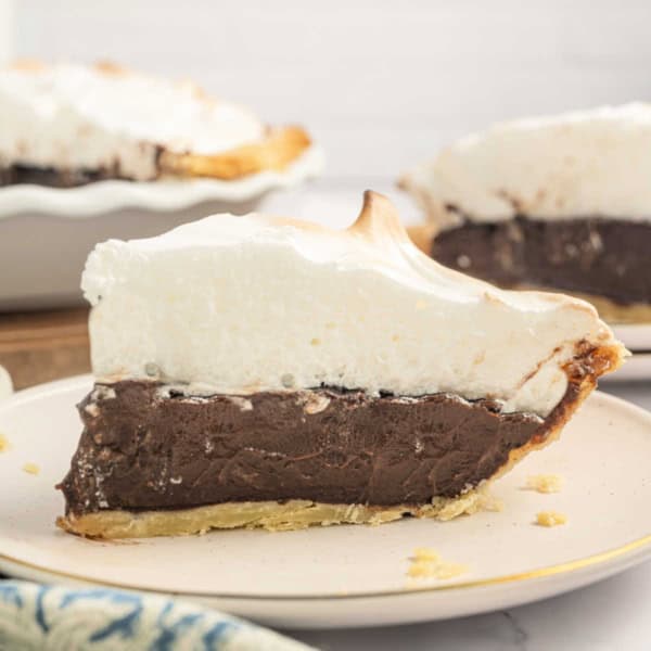 Slice of chocolate pie with meringue topping on a white plate.