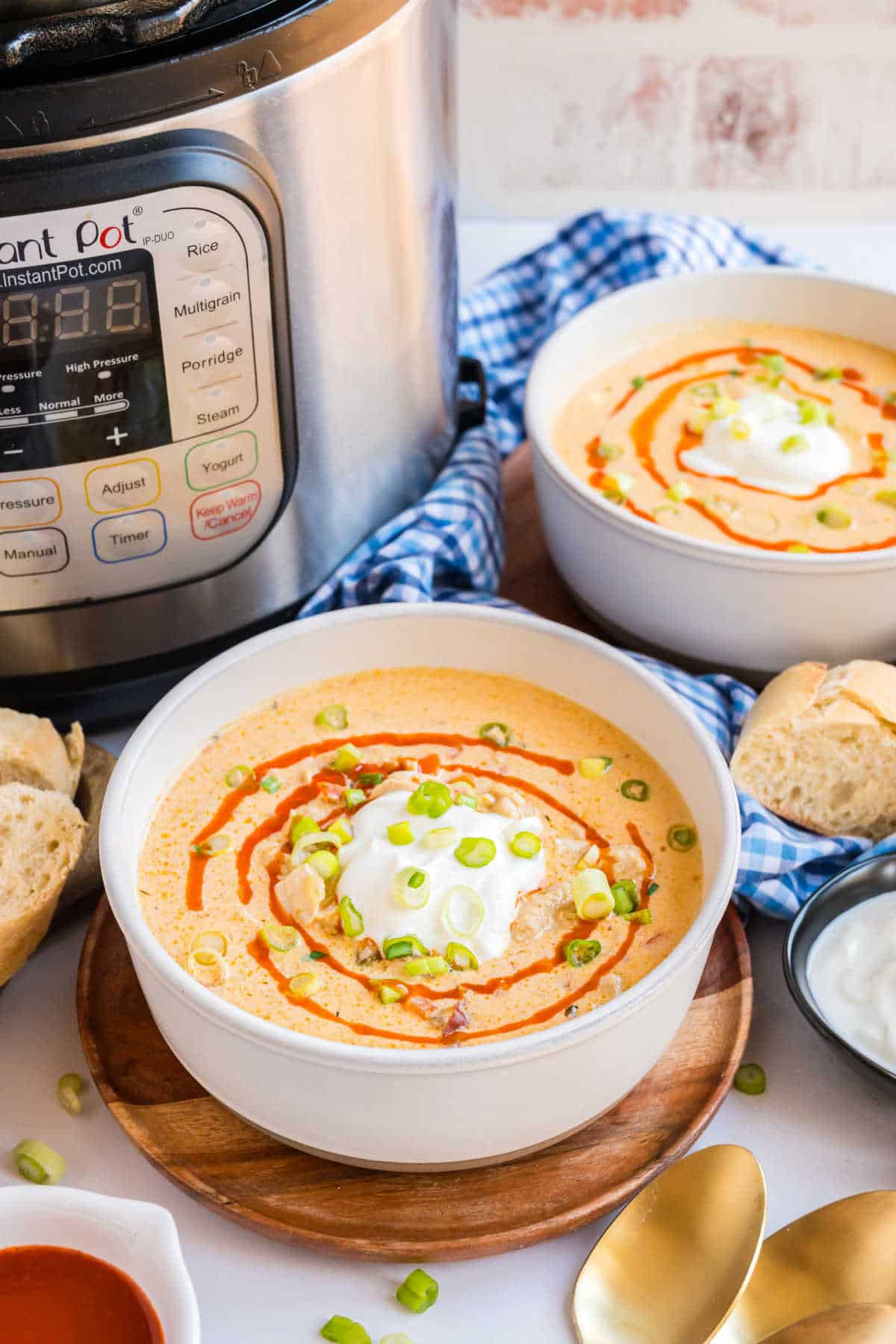 Two bowls of buffalo chicken soup with a pressure cooker in background.