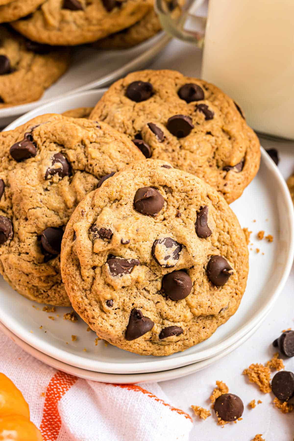 Three pumpkin chocolate chip cookies served on a white plate.