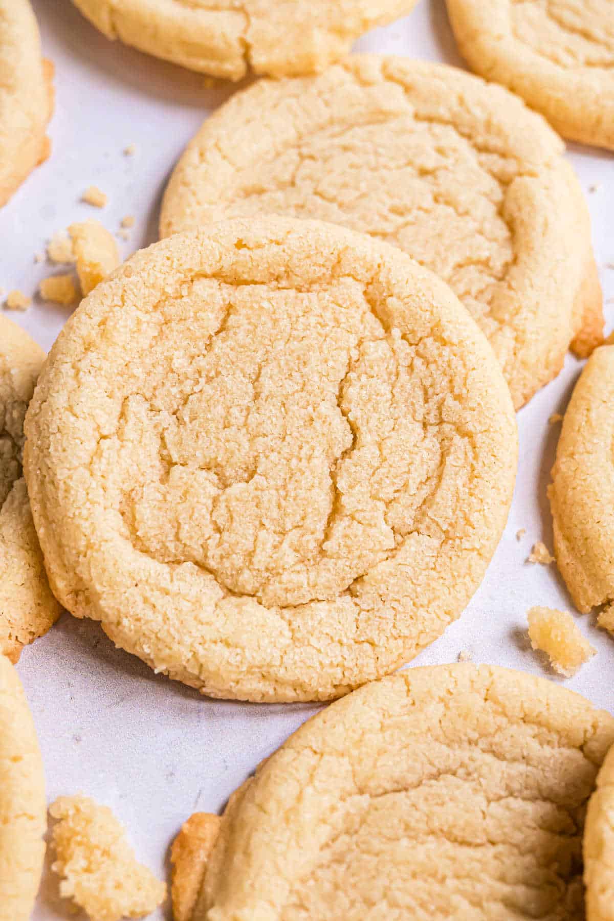 Sugar cookies stacked on parchment paper.