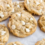 Close-up of white chocolate chip coconut cookies on a parchment-lined surface.