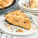 A slice of creamy peanut butter pie with a chocolate crust on a plate, sprinkled with crushed candy.