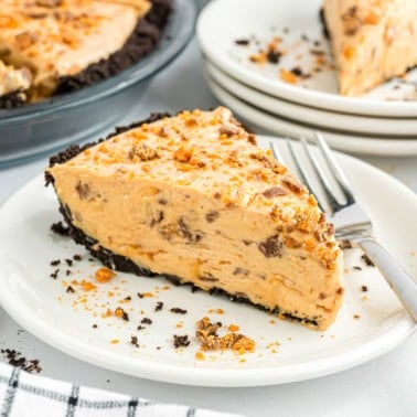 A slice of creamy peanut butter pie with a chocolate crust on a plate, sprinkled with crushed candy.