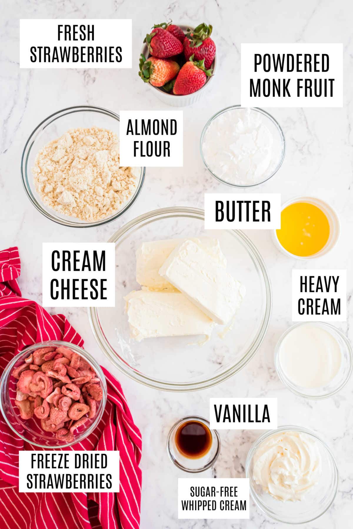 Bowls containing fresh strawberries, almond flour, butter, cream cheese, heavy cream, vanilla, and other ingredients.