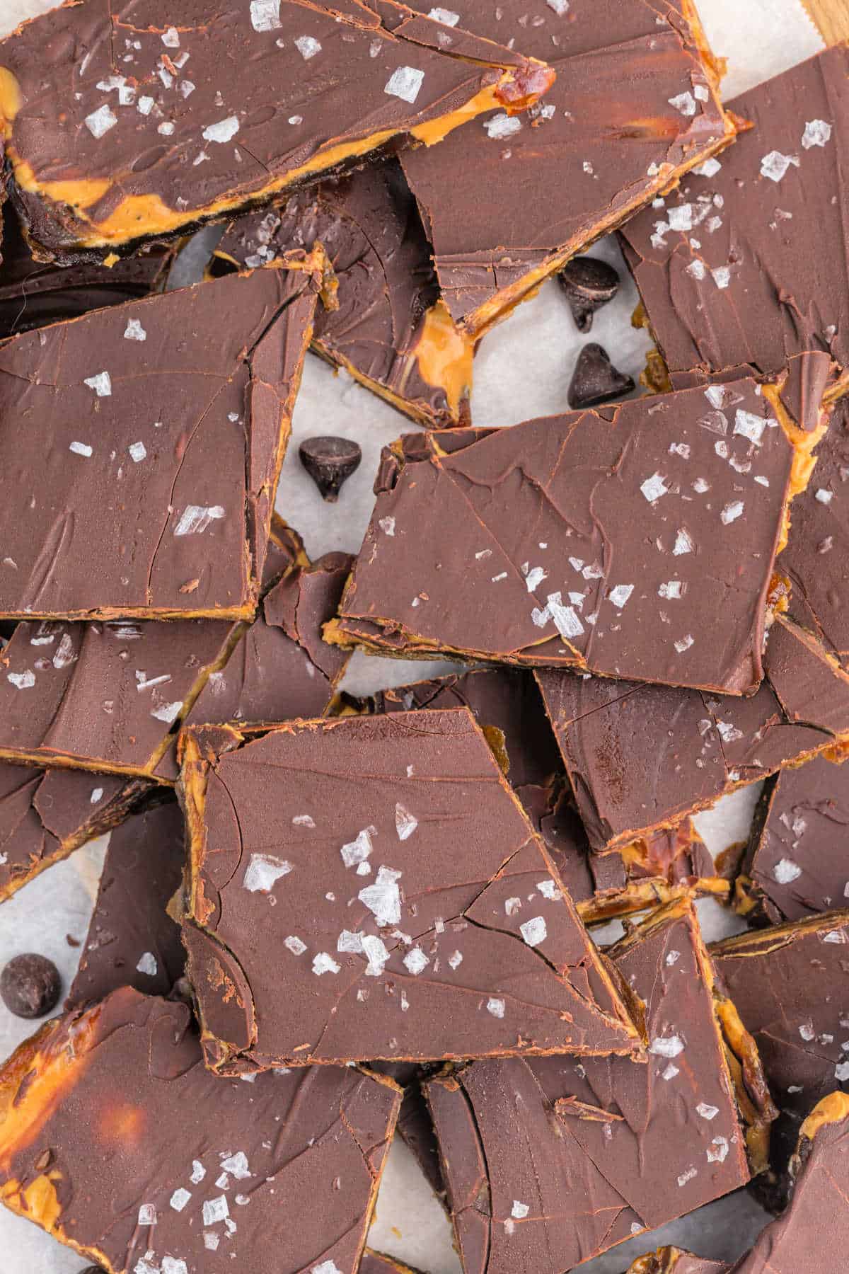 Rectangular chocolate toffee pieces topped with sea salt flakes, stacked on parchment paper.