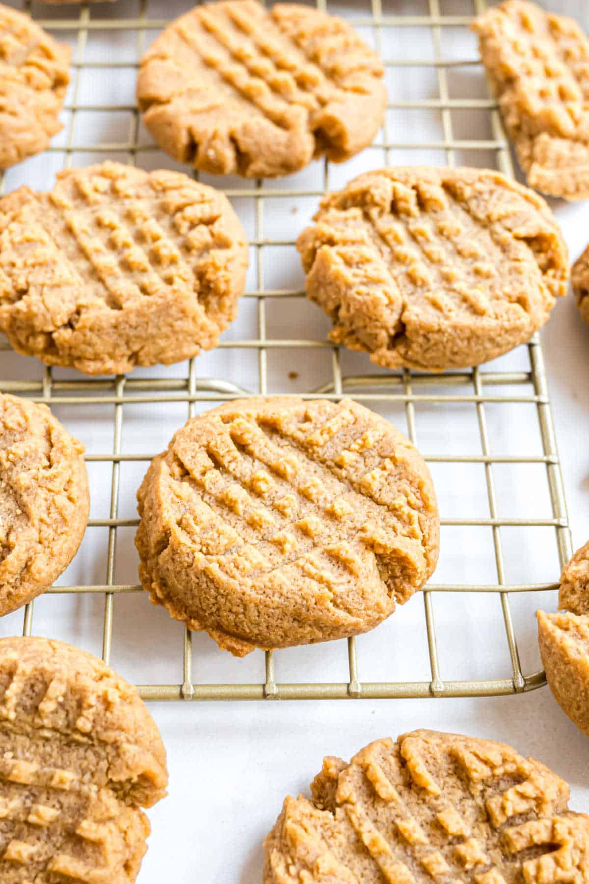 Peanut butter cookies with fork marks cooling on a wire rack.