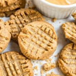 Peanut butter cookies with a crisscross pattern next to a bowl of creamy peanut butter.