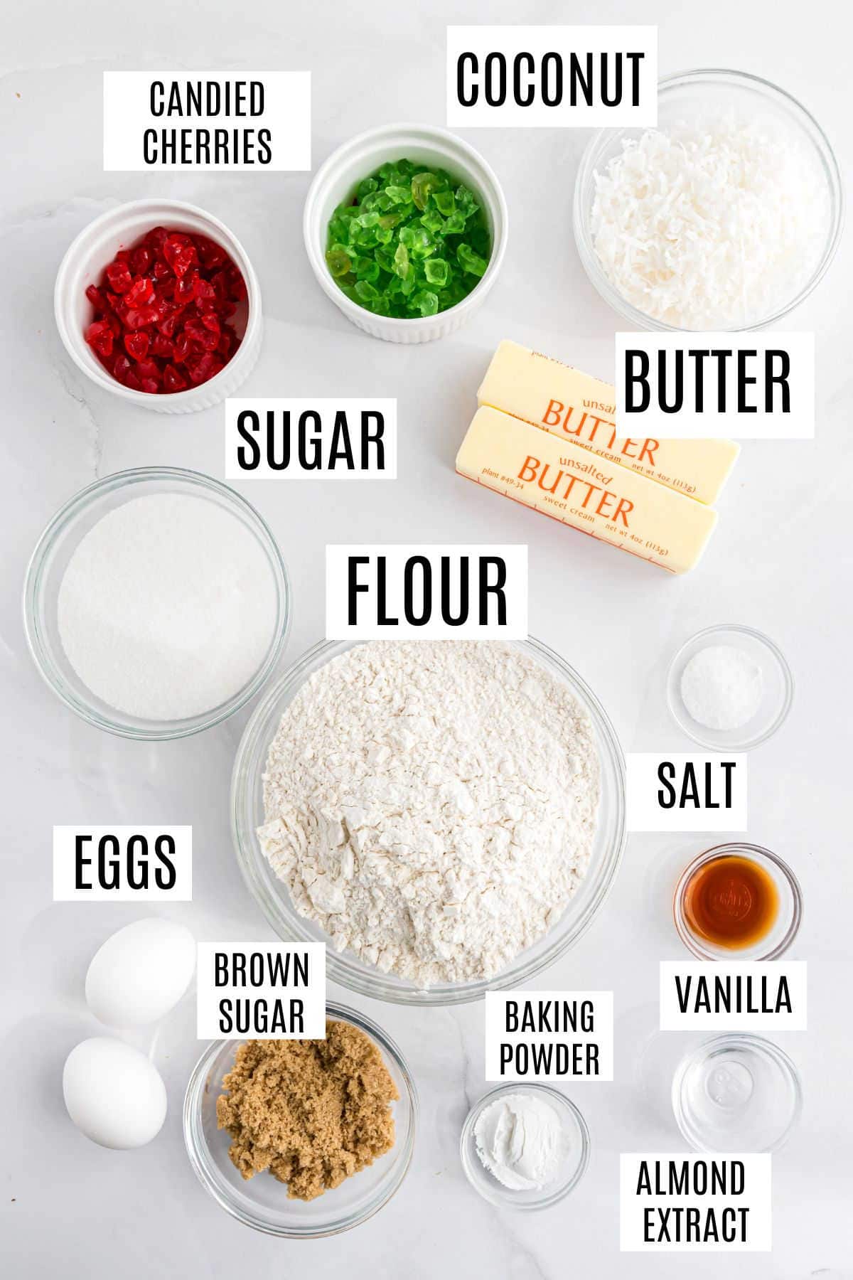 Baking ingredients in bowls labeled: cherries, coconut, butter, sugar, flour, eggs, brown sugar, salt, vanilla, almond extract—perfect for making classic Santa's Whiskers cookies.