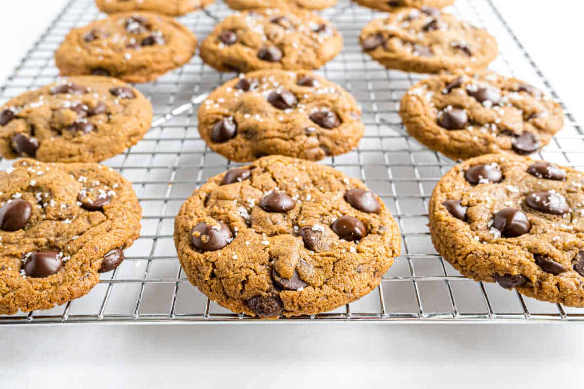 Chocolate chip cookies on a cooling rack, sprinkled with sea salt.