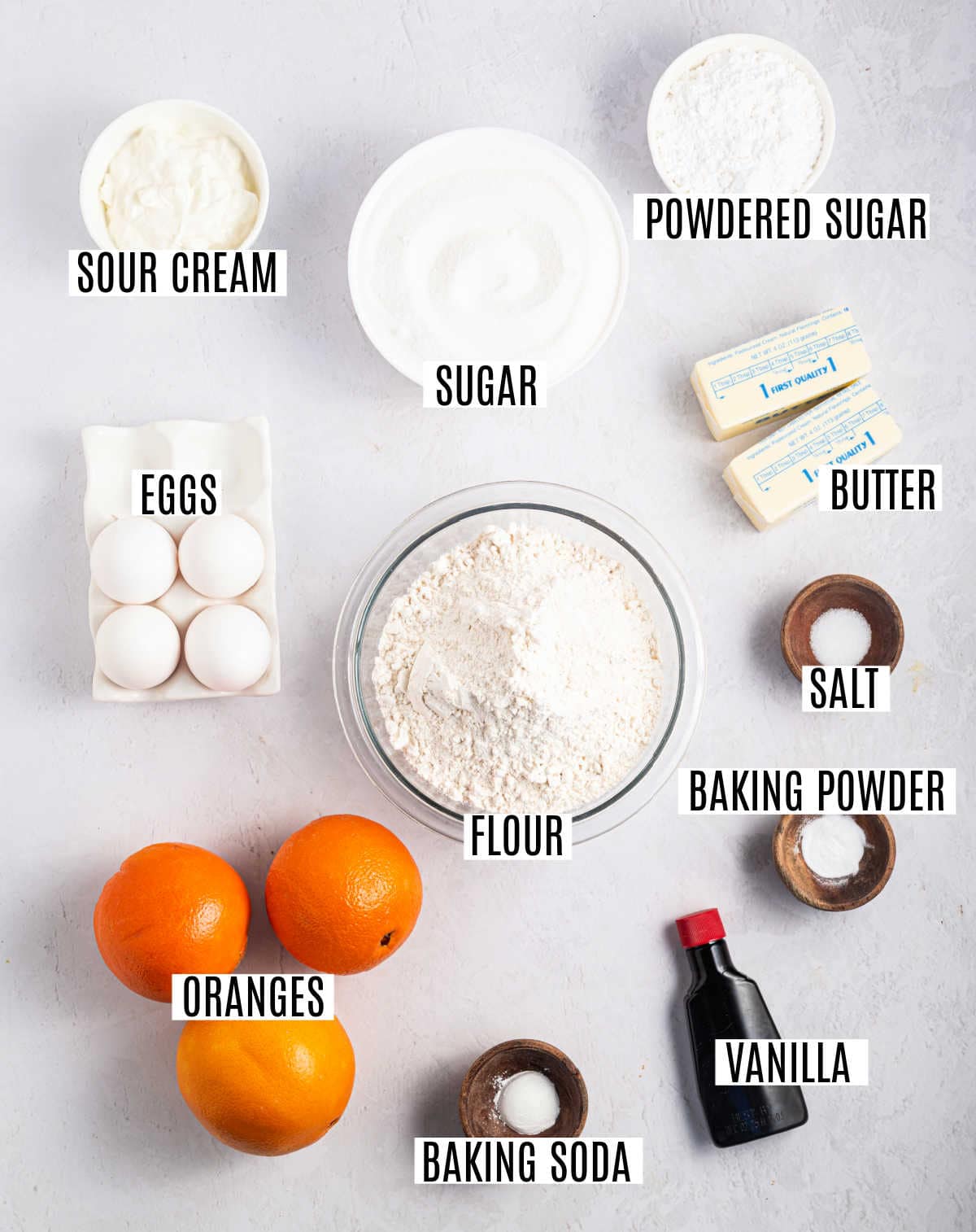 Baking ingredients labeled: sour cream, sugar, powdered sugar, eggs, flour, butter, salt, baking powder, oranges, vanilla, baking soda.