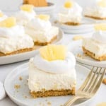 A creamy pineapple dessert bar with whipped topping and pineapple pieces on a plate with a fork.