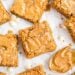 Blondie bars with crackled tops, white chocolate chips, and a spoonful of creamy peanut butter on parchment paper.
