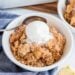 Apple crumble in a bowl with vanilla ice cream on top.