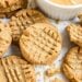 Peanut butter cookies with a crisscross pattern next to a bowl of creamy peanut butter.