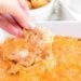 Buffalo chicken dip being scooped with a frito corn chip.