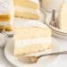 A slice of sponge cake with cream filling and powdered sugar on a white plate with a fork, inspired by a classic twinkie cake recipe.